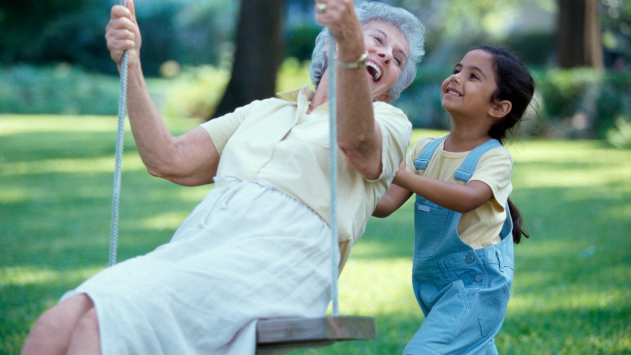 Side profile of a granddaughter pushing her grandmother on a swing