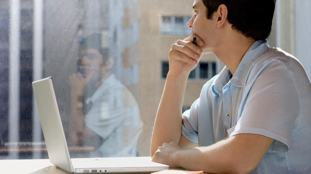 Businessman with laptop looking out window